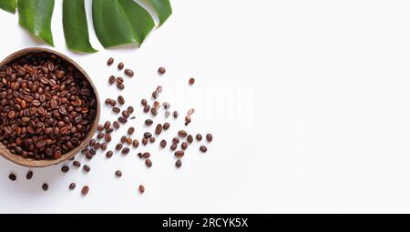 Geröstete Kaffeebohnen in einer Kokosnussschüssel und Monsterablage auf weißem Hintergrund. Draufsicht, flach liegend. Eco-Konzept von Kaffeebohnen. Speicherplatz kopieren. Green Nat Stockfoto