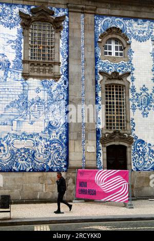 Ein Mann, der eine Zigarette raucht und an Asulejos/Keramikfliesen auf der Seite der Igreja do Carmo Kirche, Porto/Porto, Portugal, vorbeiläuft Stockfoto