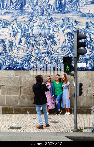 Touristen lassen sich vor den Asulejos/Keramikfliesen an der Seitenwand der Kirche Igreja do Carmo in Porto/Porto, Portugal fotografieren Stockfoto