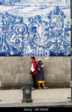 Ein junges asiatisches Paar macht ein Selfie vor den Asulejos/Keramikfliesen an der Seitenwand der Kirche Igreja do Carmo, Porto/Porto, Portugal Stockfoto