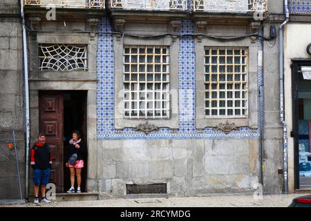 Touristen, die sich vor dem Regen in der Eingangstür eines typischen alten Hauses neben der Igreja do Carmo Kirche, Porto/Porto, Portugal, schützen Stockfoto