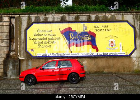 Rotes Auto parkt vor einem Werbespot für die Real Companhia Vinícola do Norte Wein-/Hafenfirma Vila Nova de Gaia, Portugal Stockfoto