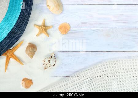 Sommerbanner mit Hut, weißem Netzgewebe, Muscheln und Seestern auf hellem Holz-Hintergrund mit Sand. Top View Sommerkomposition, Strandurlaub Concep Stockfoto