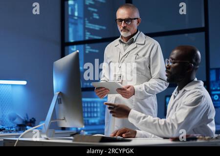 Kollegen diskutieren während ihrer Teamarbeit im Labor gemeinsam über die Entwicklung von Programmen am Computer Stockfoto