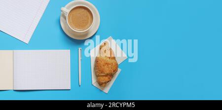 Notizblock mit leeren Blättern öffnen, Draufsicht. Bereit zum Hinzufügen von Text. Notizbuch und Kaffee mit einem Croissant auf blauem Hintergrund. Zusammensetzung des Geschäftsplans Stockfoto