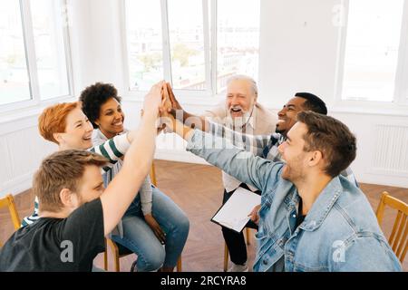 Aus der Großperspektive sehen Sie glückliche, überfreuliche multikulturelle und unterschiedliche Altersgruppen, in denen Menschen Erfolg feiern, Arbeit leisten, High Five geben, schreien, lächeln Stockfoto