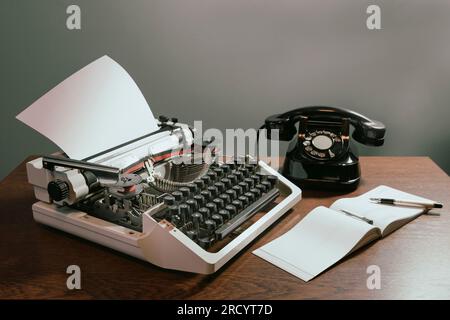 Scheckbuch mit einer leeren Seite. Retro-Konzept mit altem Telefon, Tintenstift und Schreibmaschine. In Farbe Stockfoto