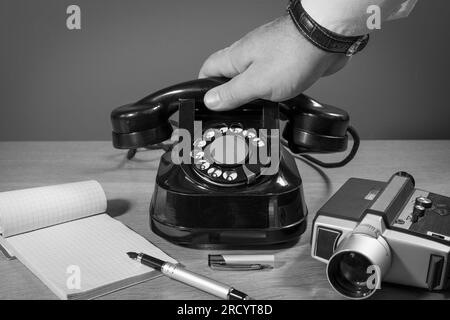 Exklusive Berichterstattung. Kommunikation der Vergangenheit. Die Hand greift nach dem Telefon. Altes Telefon auf einem Holztisch, Retro-Installation. Speicherplatz kopieren Stockfoto