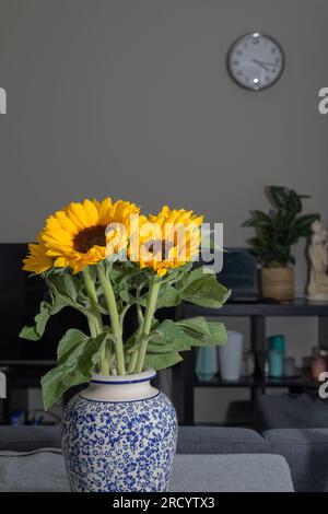 Helle Sonnenblumen in einer Vase auf einem Tisch in einer gewöhnlichen Zimmereinrichtung. Vertikal, Kopierbereich Stockfoto