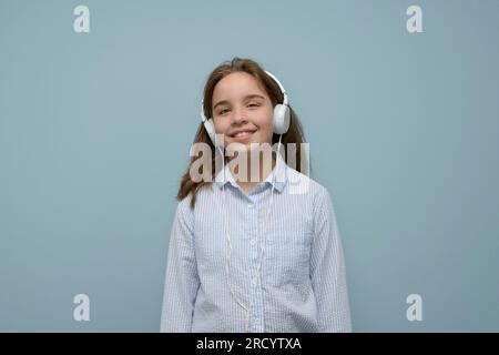 Musik genießen. Zufriedenes Teenager-Mädchen hört Musik über Kopfhörer. Ein Teenager mit Kopfhörern hört Songs über ein Headset. Positive interne e Stockfoto