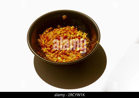 Getrocknete Chilis in einem Tonbecher mit Schatten auf weißem Hintergrund. Stockfoto