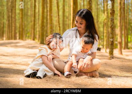Fröhliche Mutter, die im Urlaub im Park mit fröhlichen Kindern spielt Stockfoto