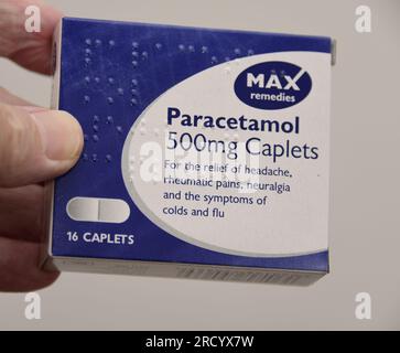 Die linke Hand eines weißen Mannes hält eine Packung Parcetamol-Tabletten der Marke Max, 16 Tabletten zu je 500mg Stück Stockfoto