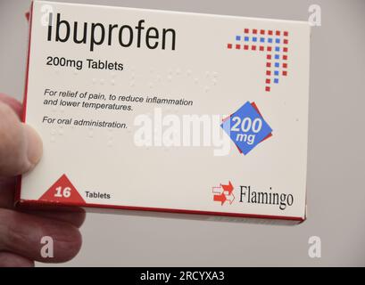 Die linke Hand eines weißen Mannes hält eine Packung des Schmerzmittels Ibuprofen, 16 Tabletten zu je 200 mg Stockfoto