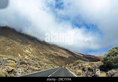 Wolken über den Bergen in der Nähe des Vulkans Teide auf der Insel Teneriffa, Bewegung, verschwommen, Blick aus dem Auto, Track in the Clouds, Spanien, natürliches Bac Stockfoto