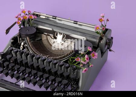 Vintage-Schreibmaschine auf lilafarbenem Hintergrund, Nahaufnahme Stockfoto