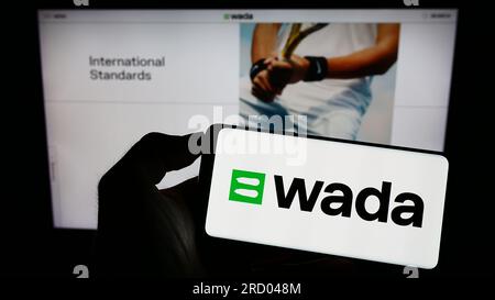 Person, die ein Handy mit dem Logo der Organisation World Anti-Doping Agency (WADA) auf dem Bildschirm vor der Webseite hält. Konzentrieren Sie sich auf das Display des Telefons. Stockfoto
