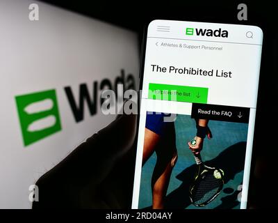 Person mit Smartphone und Webseite der Organisation World Anti-Doping Agency (WADA) auf dem Bildschirm mit Logo. Konzentrieren Sie sich auf die Mitte des Telefondisplays. Stockfoto