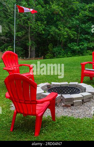 Rote Stühle um eine Feuerstelle im Muskoka-Bezirk von Ontario, Kanada Stockfoto