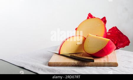 Geschnittener Edamskäse-Kopf, mit roter Wachsbeschichtung bedeckt, Kopierraum. Stockfoto