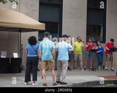 Fußgänger halten an, um Drop the Mic A Capella Street Performers in Frederick, Maryland, 3. Juni 2023, © Katharine Andriotis zu lauschen Stockfoto