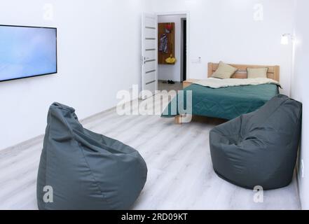 2 rahmenlose graue Sessel mit fernseher mit Doppelbett, skandinavisches Design, Schlafzimmer, Inneneinrichtung, Minimalismus Stockfoto