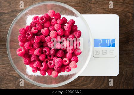 Glasschale mit roten Himbeeren auf Küchenwaage Stockfoto