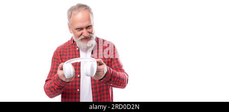 Moderner Musikliebhaber 60s erwachsener Mann mittleren Alters in einem stilvollen Hemd hört neue Musik über Kopfhörer Stockfoto