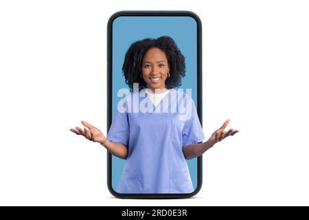 Fröhliche junge schwarze Ärztin Krankenschwester in blauer Uniform hält leeren Platz auf den Händen auf dem großen Smartphone-Bildschirm Stockfoto