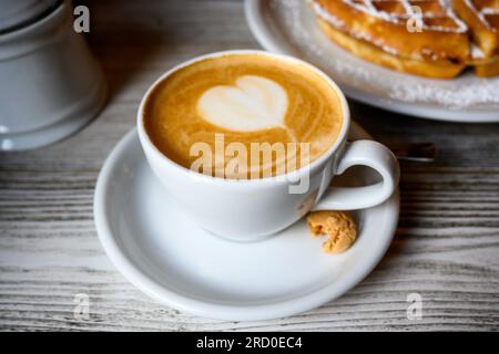 eine tasse Cappuccino mit einem kleinen Keks an der Seite Stockfoto