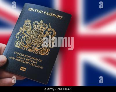 Hand mit britischem Pass vor dem Union Jack. Reisedokument für Ungebundenes Königreich und Nordirland Stockfoto