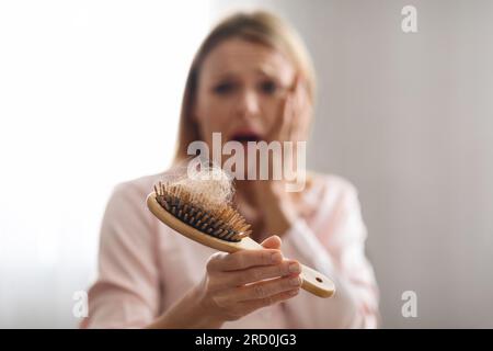 Besorgte, Reife Frau Mit Haarausfall, Kamm Voller Gefallener Haare Stockfoto