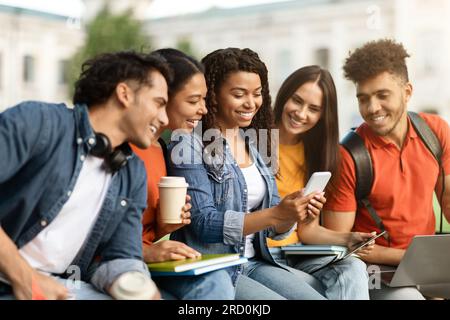 Campus Freizeit. Multiethnische Gruppe von Schülern, die sich im Freien entspannen Stockfoto