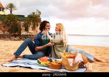 Porträt Eines Romantischen Jungen Paares, Das Ein Picknick Am Strand In Der Nähe Des Meeres Macht Stockfoto
