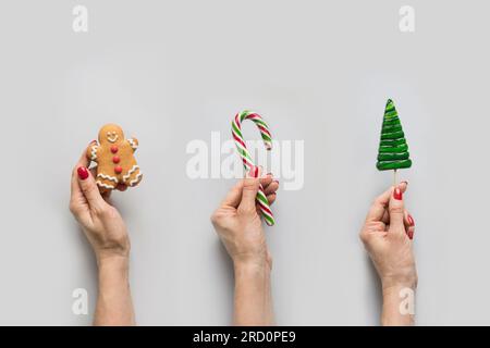 Traditionelles Weihnachtsessen in weiblicher Hand mit Lebkuchen, Lutscher, Zuckerrohr. Weihnachtsgrußkarte. Stockfoto