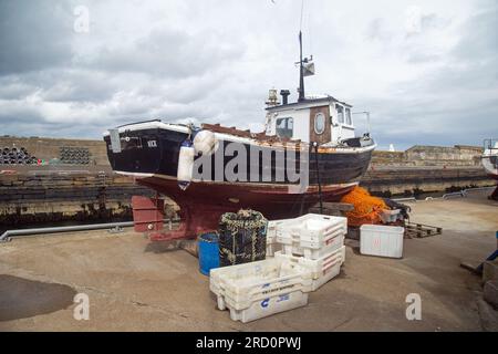 Wick, Caithness, Schottland, Juli 2. 2023, Ein kleines Fischerboot auf dem Trockendock am Hafen. Stockfoto