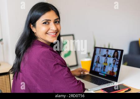 Fröhliche Asiatin, die zu Hause an einem Notebook arbeitet Stockfoto