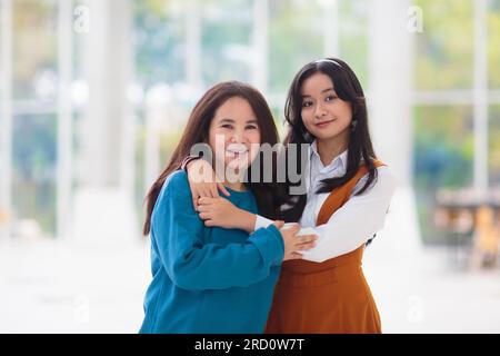 Asiatische mutter und Tochter reden und umarmen. Mutter und Teenager in einem weißen, sonnigen Zimmer. Familienporträt. Stockfoto