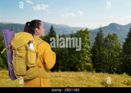 Glücklicher Tourist mit gelbem Rucksack in den Bergen Stockfoto