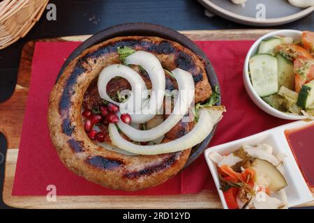 Draufsicht, Locken von Kupati, georgianische würzige Wurst mit ausgeprägtem Geschmack, dazu Zwiebeln und Barbeeren. Stockfoto