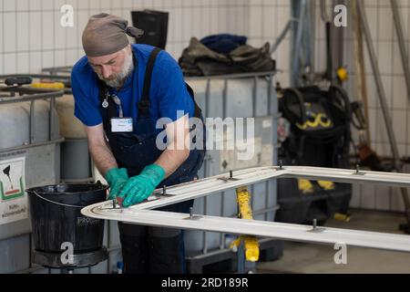 Kassel, Deutschland. 12. Juli 2023. Ein Mitarbeiter der Hübner-Werke wäscht den Rahmen eines Übergangssystems der ICE 3-Flotte. Die Hübner-Gruppe aus Kassel in Nordhessen schließt die Renovierung der Übergänge für die gesamte ICE 3-Flotte der Deutschen Bahn ab. (Dpa: „Fresh up: Modernization of the ICE 3 Fleet are coming completion“) Kredit: Swen Pförtner/dpa/Alamy Live News Stockfoto