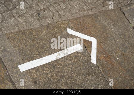 Weißer Marker aus Klebeband auf einem Fußweg im Stadtzentrum von Berlin als Wegweiser für eine Veranstaltung Stockfoto