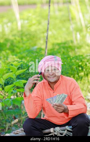Glücklicher indischer Bauer, Bauer, der indische Rupien in der Hand hält, intelligente Landwirtschaft Stockfoto