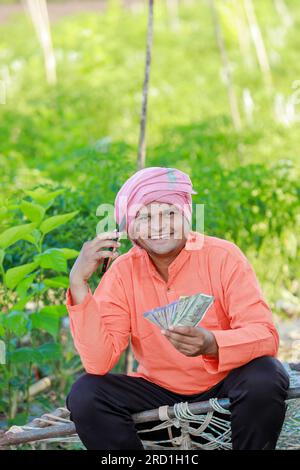 Glücklicher indischer Bauer, Bauer, der indische Rupien in der Hand hält, intelligente Landwirtschaft Stockfoto
