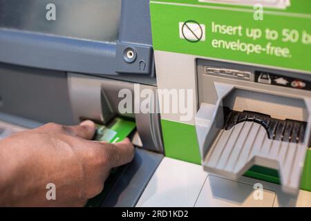 Die Hand eines Mannes, der eine Kreditkarte in den Geldautomaten einsteckt, die Plastikkarte des Geldautomaten, um Geld abzuheben, finanziert das Konzept der Geldbank. Geldautomat-Credi Stockfoto