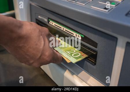 Barabhebung an einem Geldautomaten. Geld in den Händen von Nahaufnahmen. Kanadische Dollarscheine und Geldautomat. Geld in den Händen. Die Hand eines Mannes, der Geld abhebt. F Stockfoto