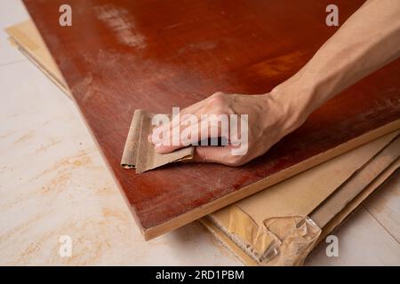 Entfernen Sie die Farbe vom Holztisch mit Schleifpapier Stockfoto