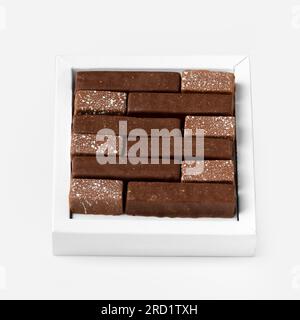 Handgemachte Süßigkeiten aus dunkler und milchiger Schokolade in Gold und Silber in einem Paket auf weißem Hintergrund. Stockfoto