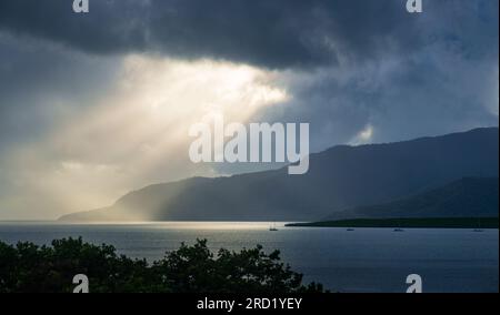 Sonnenlicht bricht durch stürmische Wolken auf das sonnenbeleuchtete Meer. Stockfoto