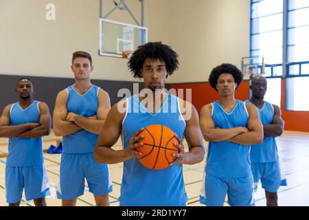 Porträt von verschiedenen männlichen Basketballspielern, die im Fitnessstudio blaue Sportkleidung tragen Stockfoto